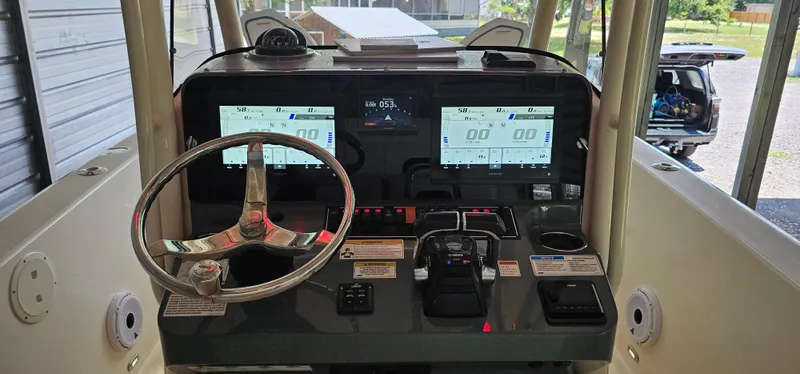 Slide: The Image of 2014 Pursuit C 260 Center Console boat dashboard with dual displays and steering wheel. - 34
