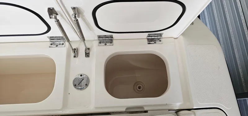 Slide: The Image of 2014 Pursuit C 260 Center Console boat storage compartments with open lids. - 37