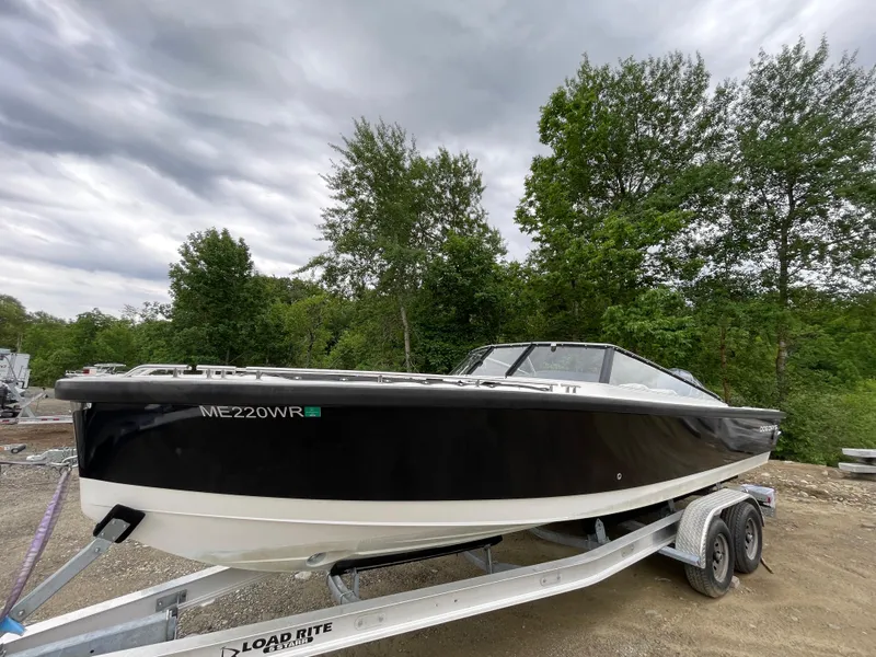 Slide: The Image of 2016 Draco 27 RS boat on Load Rite trailer, black and white hull, parked outdoors. - 0