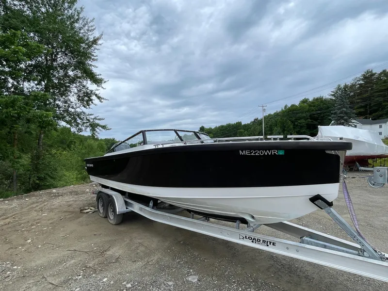Slide: The Image of 2016 Draco 27 RS boat on a trailer, parked outdoors under a cloudy sky. - 10