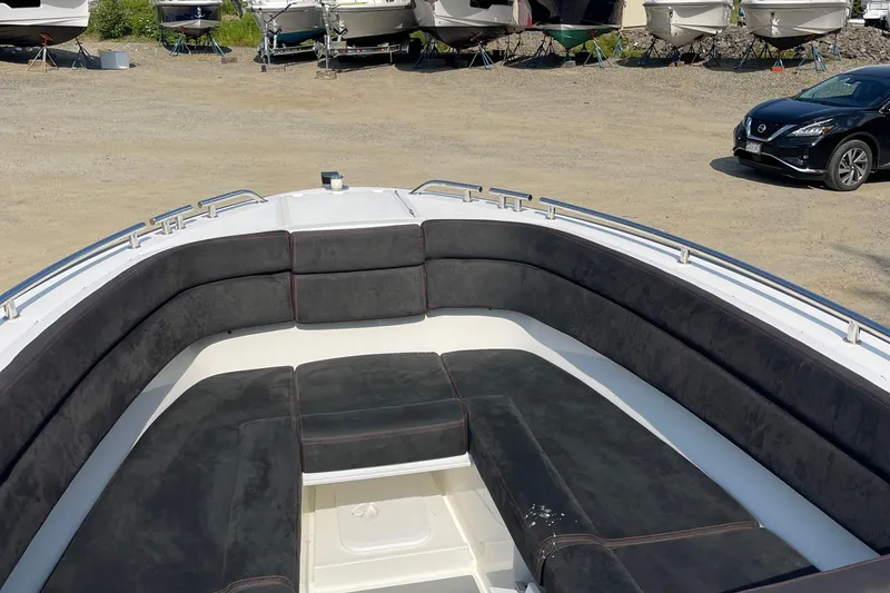 Slide: The Image of 2016 Draco 27 RS boat with black cushioned seating in a boatyard. - 21