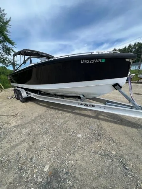 Slide: The Image of 2016 Draco 27 RS boat on a trailer, black and white hull, outdoors. - 8