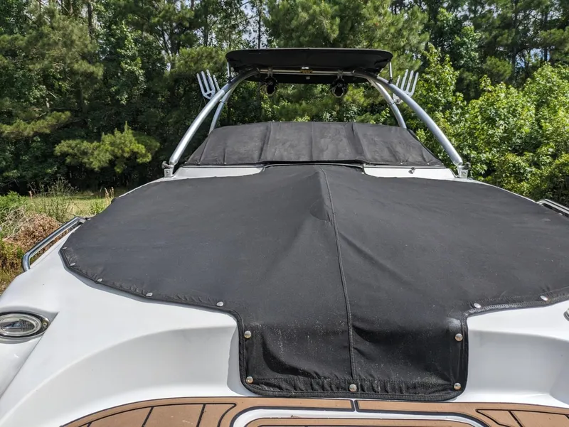 Slide: The Image of 2012 Four Winns F244 boat with black cover, rear view, parked outdoors. - 11