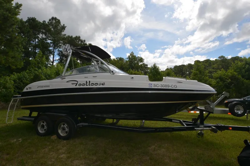 Slide: The Image of 2012 Four Winns F244 boat on trailer in grassy area with trees. - 2