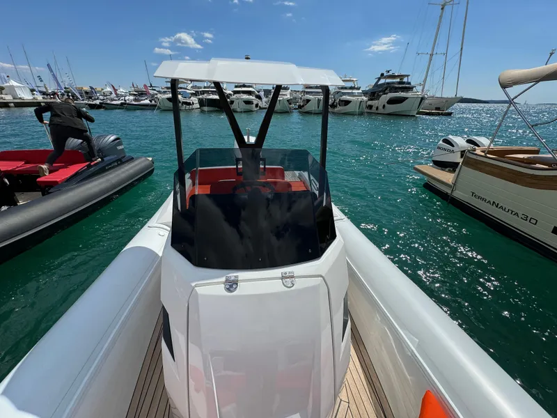 Slide: The Image of 2025 SuperRib Open 27 boat docked in a marina with other yachts. - 15