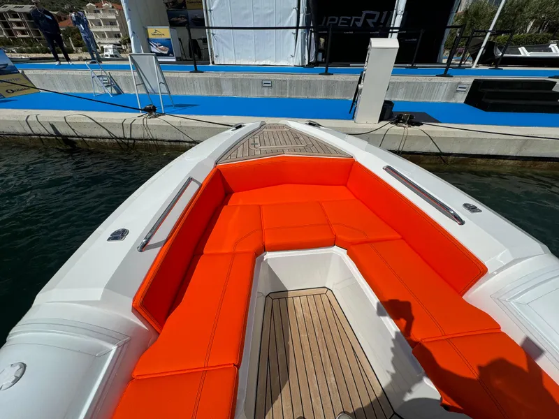 Slide: The Image of SuperRib Open 27 (2025) boat with orange seating and wooden deck at a marina. - 17