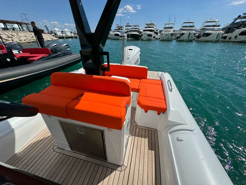 Slide: The Image of 2025 SuperRib Open 27 boat with orange seating, docked at a marina. - 19