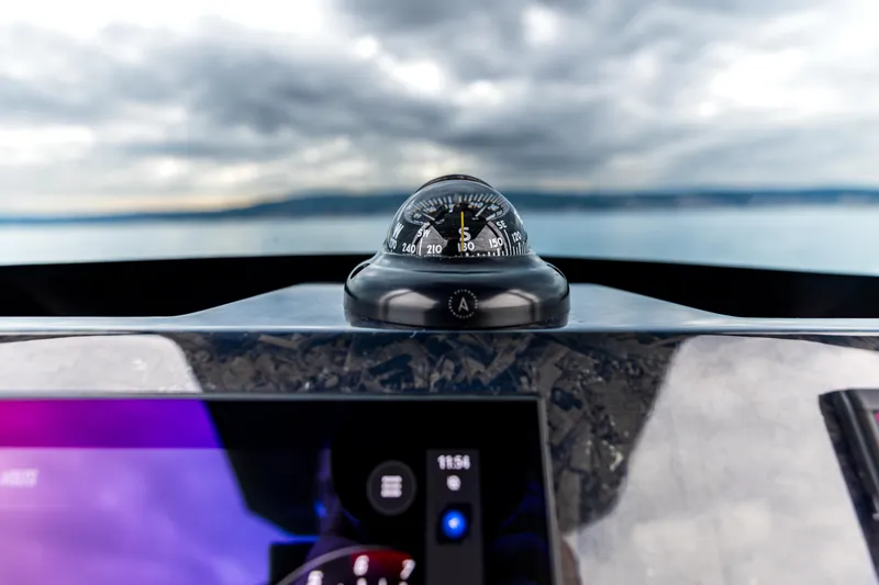 Slide: The Image of Compass and dashboard of 2026 SuperRib Open 27 boat with scenic ocean view. - 2