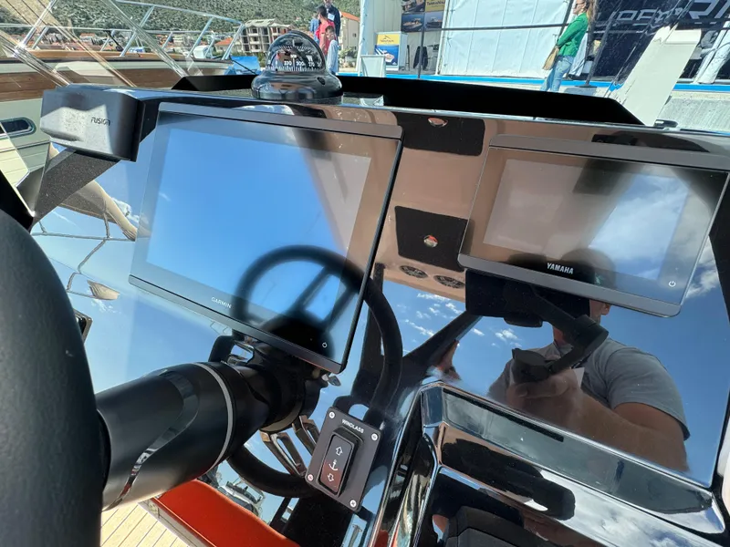 Slide: The Image of Control panel of 2025 SuperRib Open 27 boat with navigation screens and steering wheel. - 27