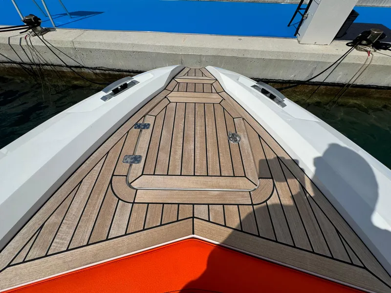 Slide: The Image of 2025 SuperRib Open 27 boat deck with teak finish at dock. - 29