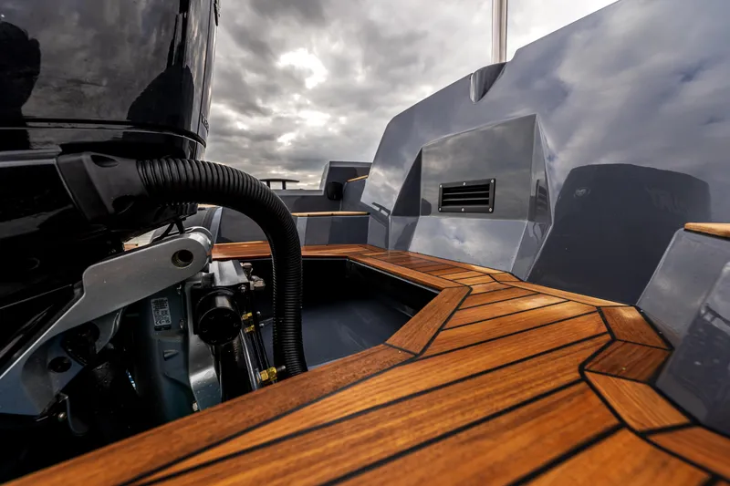 Slide: The Image of 2026 SuperRib Open 27 boat with sleek wooden deck and modern design under cloudy sky. - 5