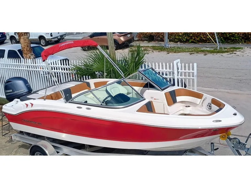 Slide: The Image of 2024 Chaparral 19 SSi OB boat with red and white exterior on a trailer. - 2