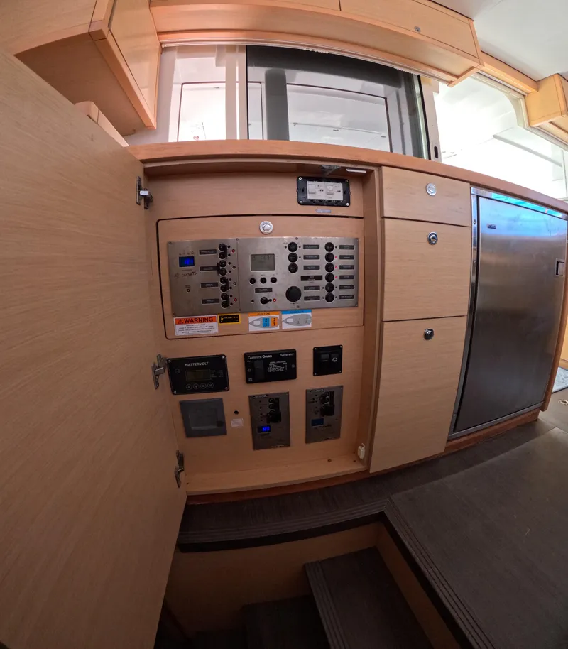Slide: The Image of Control panel inside a 2014 Lagoon 450 catamaran, featuring wooden cabinetry and modern appliances. - 14