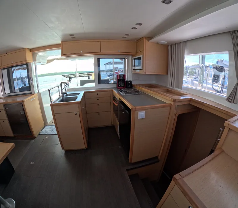 Slide: The Image of Interior of 2014 Lagoon 450 catamaran kitchen with modern appliances and wooden cabinetry. - 19