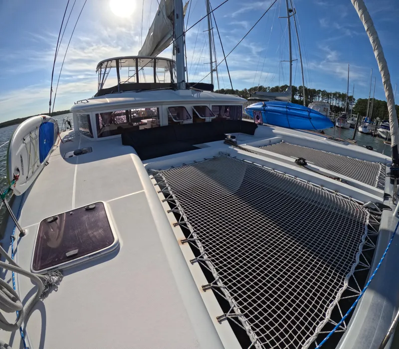 Slide: The Image of 2014 Lagoon 450 catamaran with sunlit deck and netting, docked in a marina. - 2