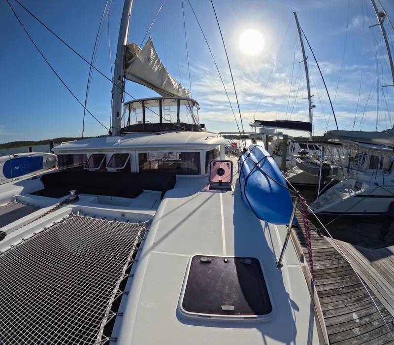 Slide: The Image of 2014 Lagoon 450 catamaran docked under bright sun, featuring spacious deck and sails. - 3