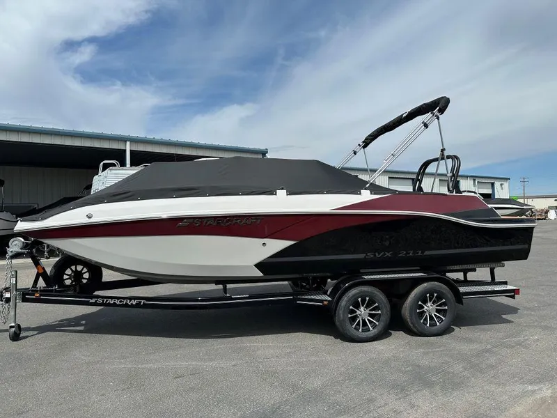 Slide: The Image of 2024 Starcraft SVX 211 OB boat on a trailer, covered and parked outdoors. - 2