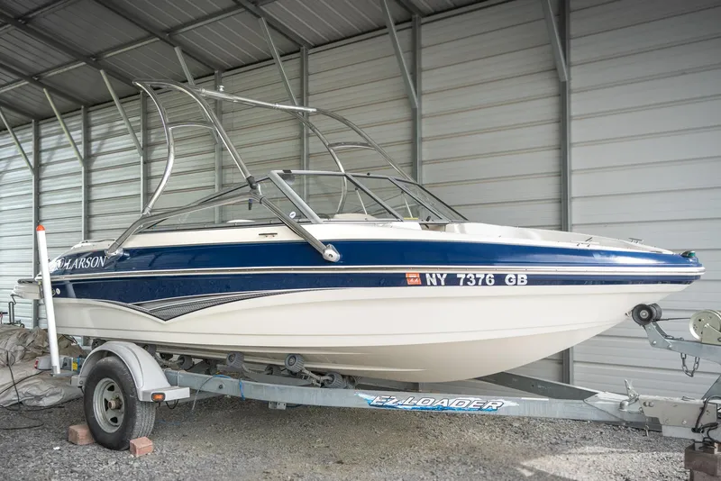 The Image of 2010 Larson LX 1850 boat on trailer in covered storage. - 1