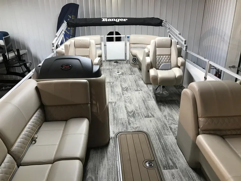 Slide: The Image of 2024 Ranger Reata 243C pontoon boat interior with beige seating and wood-style flooring. - 8