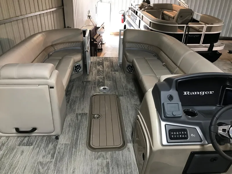 Slide: The Image of 2024 Ranger Reata 243C pontoon boat interior with beige seating and modern dashboard. - 9