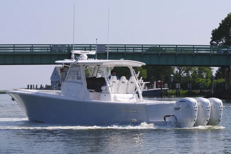 Slide: The Image of 2025 Regulator 37 boat cruising under a bridge with triple outboard engines. - 10