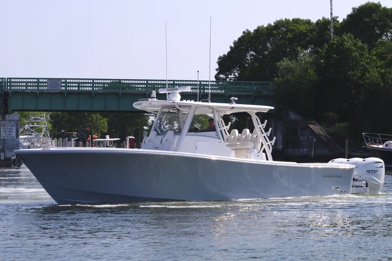 Slide: The Image of 2025 Regulator 37 boat cruising on water near a green bridge. - 11