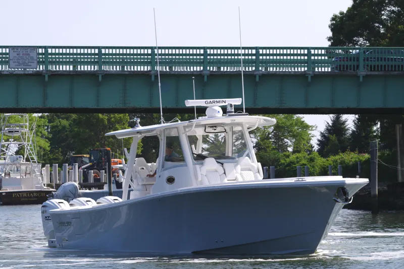 Slide: The Image of 2025 Regulator 37 boat cruising under a bridge on a sunny day. - 2