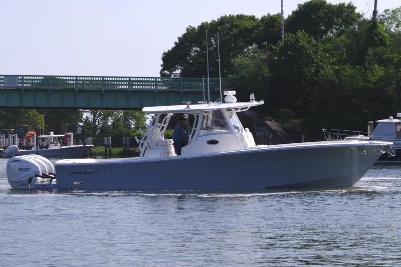 Slide: The Image of 2025 Regulator 37 boat cruising on a calm river near a green bridge. - 4