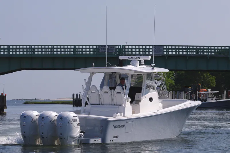 Slide: The Image of 2025 Regulator 37 boat with triple Yamaha engines cruising under a bridge. - 7