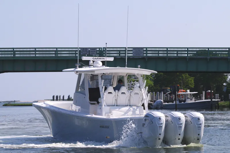Slide: The Image of 2025 Regulator 37 boat with four outboard engines cruising under a bridge. - 9