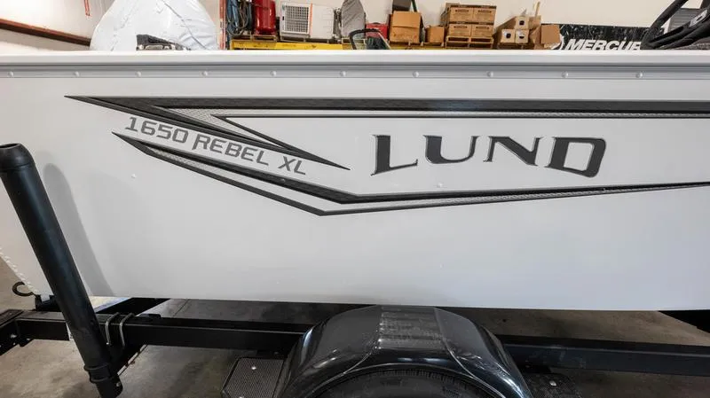 Slide: The Image of 2025 Lund 1650 Rebel XL SS boat side view in a garage. - 16