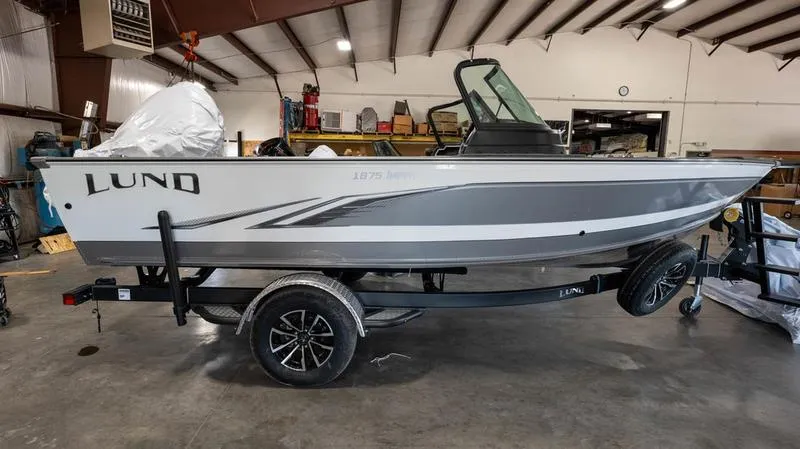 The Image of 2024 Lund 1875 Impact XS Sport boat in a warehouse on a trailer. - 1