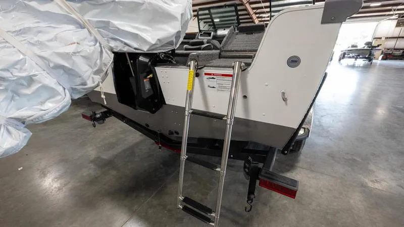 Slide: The Image of 2024 Lund 1875 Impact XS Sport boat rear view with ladder in warehouse. - 27