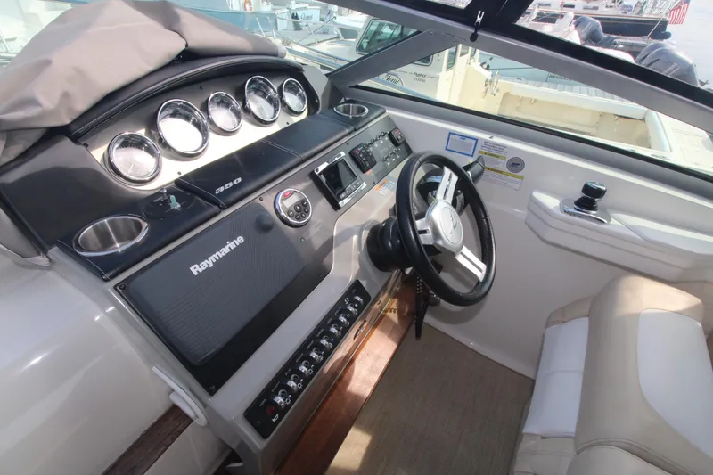 Slide: The Image of 2014 Sea Ray 350 Sundancer helm with gauges, steering wheel, and navigation equipment. - 18
