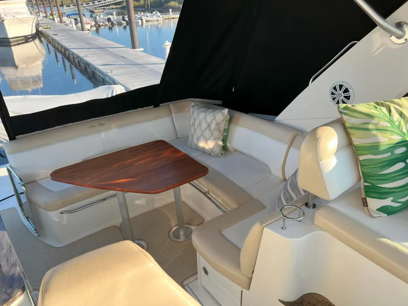 Slide: The Image of 2014 Sea Ray 350 Sundancer interior with seating, table, and cushions at marina. - 21