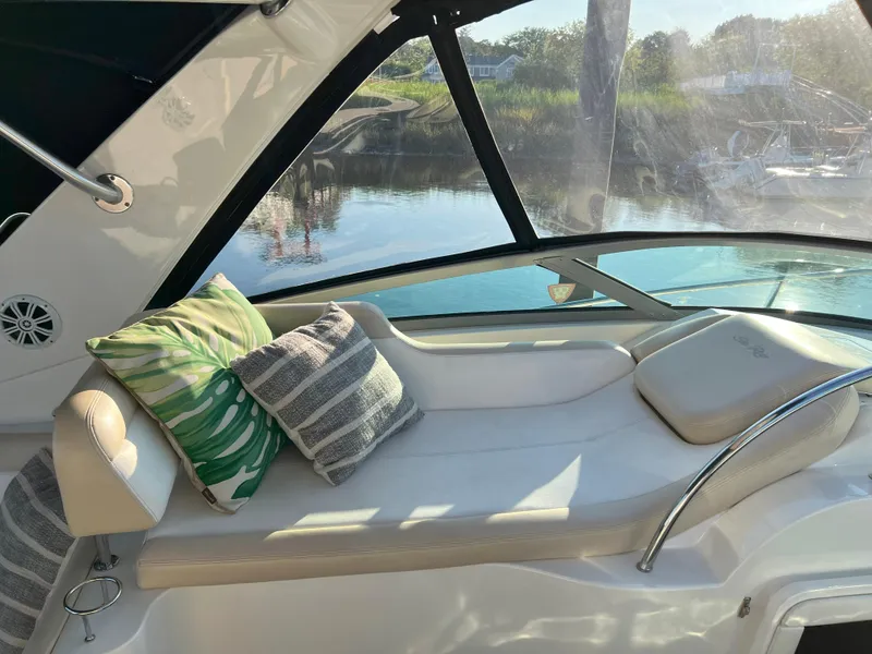Slide: The Image of 2014 Sea Ray 350 Sundancer interior with cushioned seating and decorative pillows by the water. - 22
