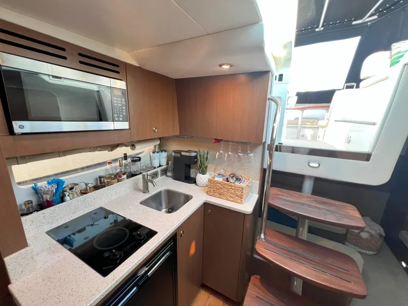 Slide: The Image of 2014 Sea Ray 350 Sundancer yacht interior kitchen with modern appliances and wooden cabinetry. - 39