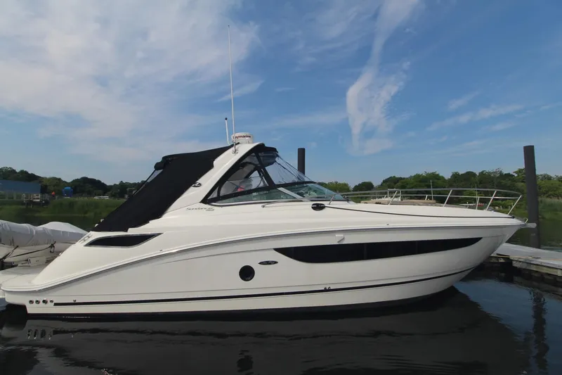 Slide: The Image of 2014 Sea Ray 350 Sundancer boat docked on calm water under a clear sky. - 5