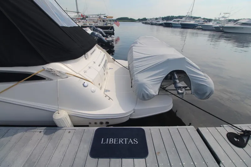 Slide: The Image of 2014 Sea Ray 350 Sundancer docked, covered dinghy, "Libertas" mat on pier. - 8