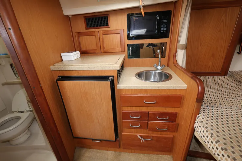 Slide: The Image of 2007 Luhrs 32 Open galley with sink, microwave, fridge, and storage drawers. - 26