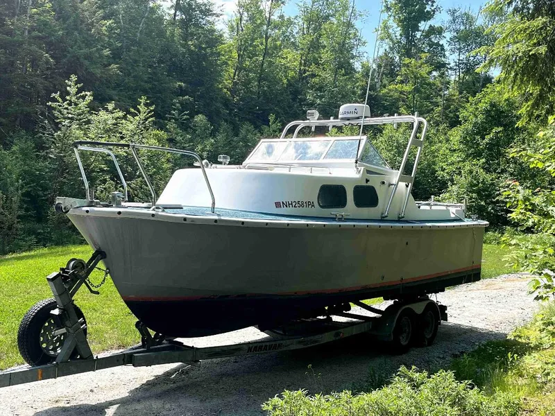 Slide: The Image of 1990 MTI 26-Foot US NAVY Personnel Boat on a trailer in a wooded area. - 10