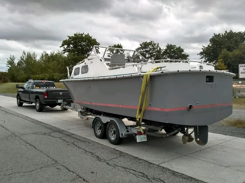 Slide: The Image of 1990 MTI 26-Foot US NAVY Personnel Boat on trailer, towed by a black pickup truck. - 47