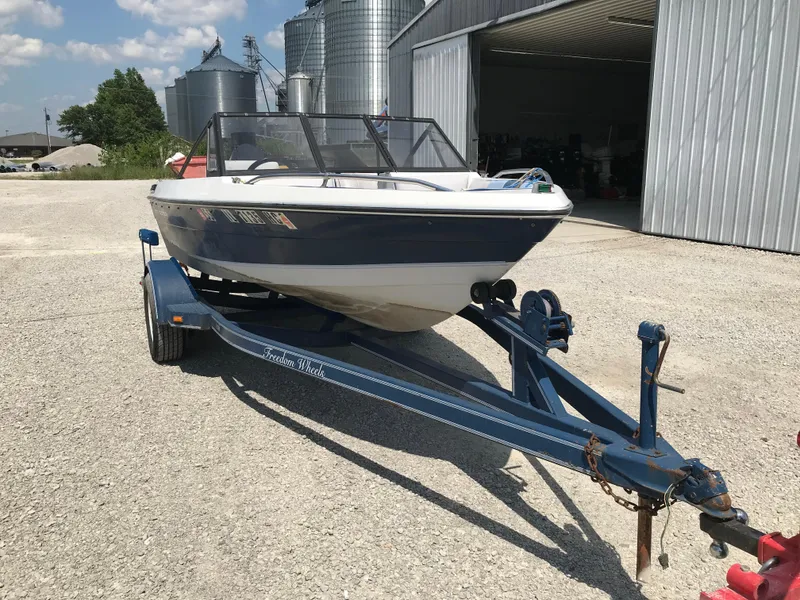 Slide: The Image of 1990 Sea Sprite 155BR boat on a trailer in a gravel lot near metal buildings. - 4