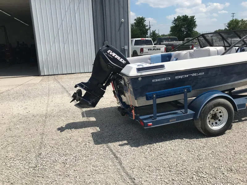 Slide: The Image of 1990 Sea Sprite 155BR boat with Evinrude motor on trailer outside a garage. - 7