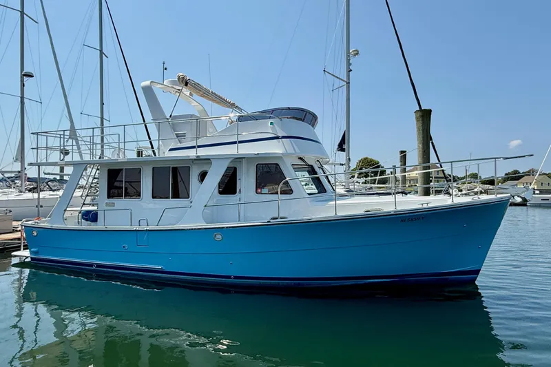 Slide: The Image of 2024 Helmsman Trawlers Helmsman 38 Sedan in marina, blue hull, sunny day. - 21