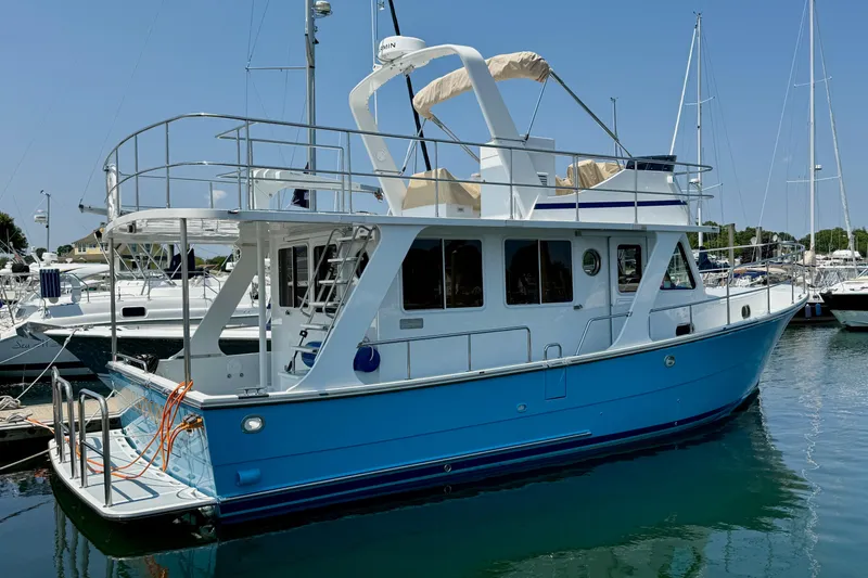 Slide: The Image of 2024 Helmsman Trawlers 38 Sedan in marina, blue hull, modern design, clear sky. - 25