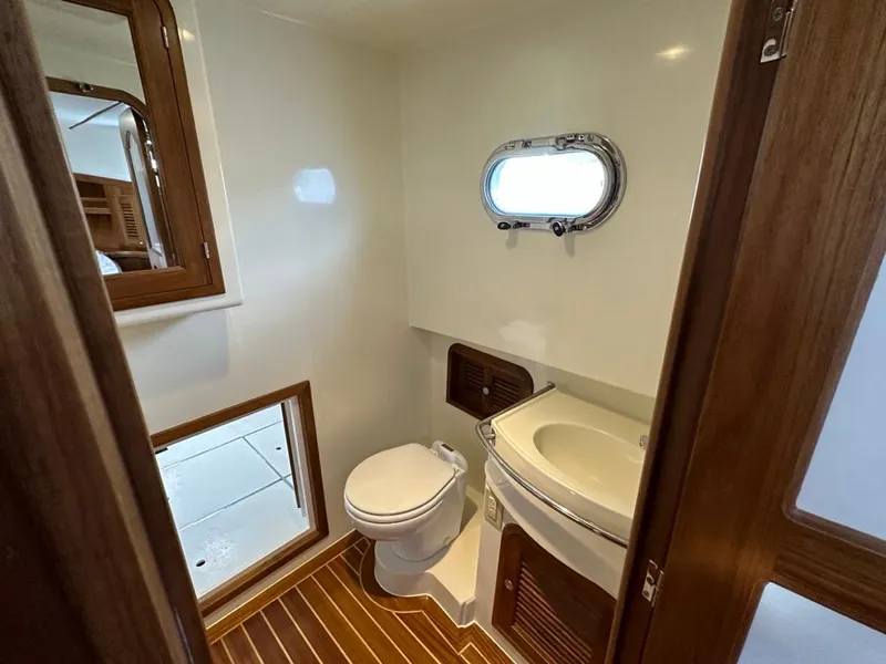 Slide: The Image of 2024 Helmsman 38 Sedan bathroom with wood accents and porthole. - 7