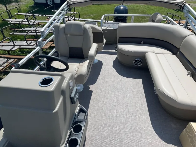 Slide: The Image of 2024 Sun Tracker Bass Buggy 18 DLX pontoon boat interior with beige seating and steering console. - 11