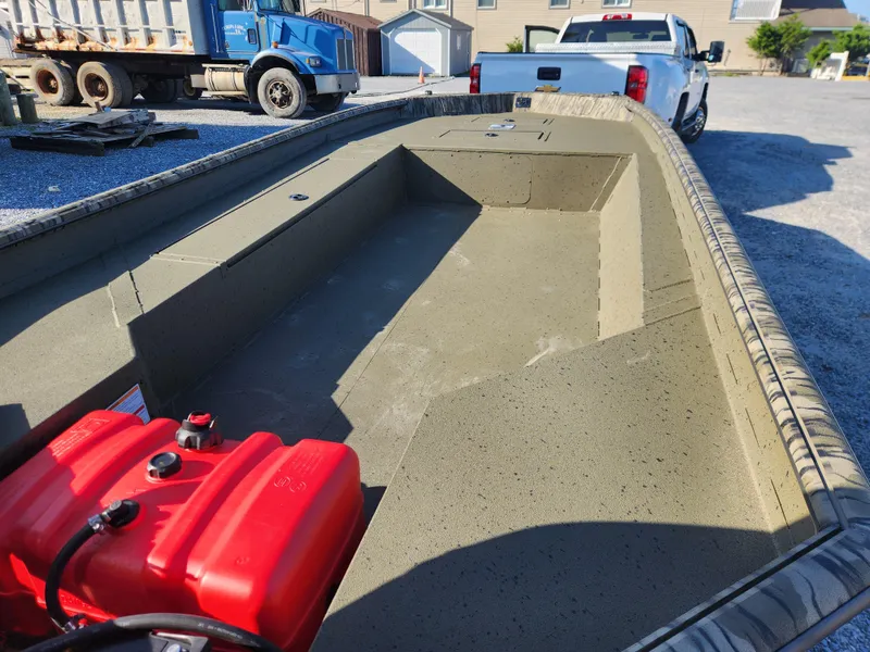 Slide: The Image of 2024 SeaArk 1960 Slayer Pro boat interior with red fuel tank, parked on gravel. - 3