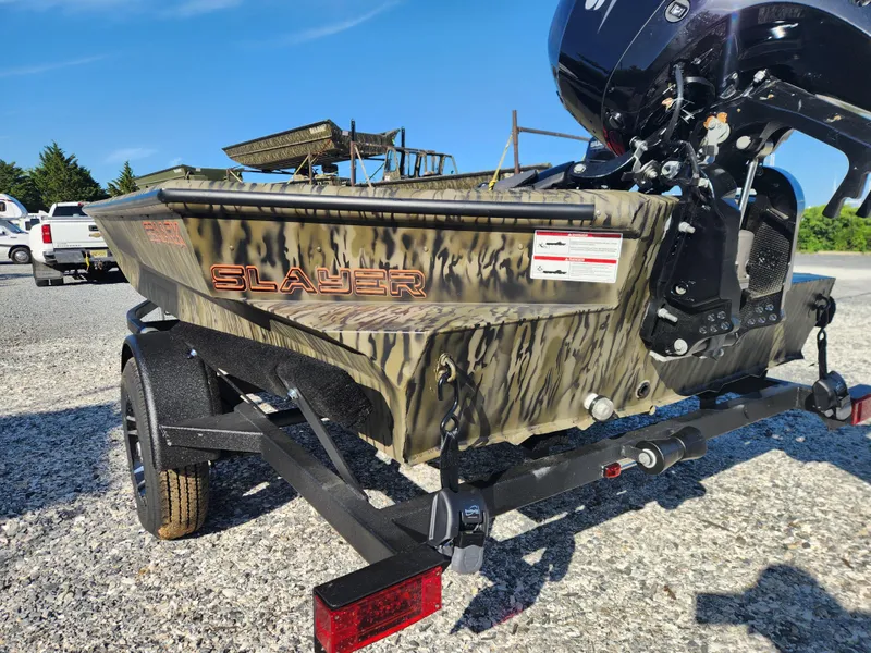 Slide: The Image of 2024 SeaArk 1960 Slayer Pro boat on trailer, camo design, outboard motor, sunny day. - 6